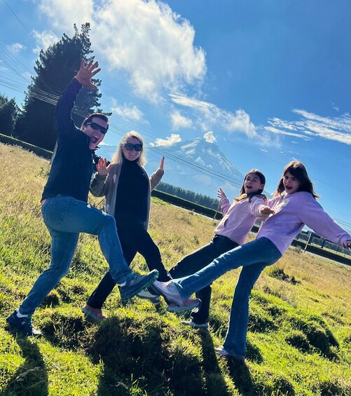 A group of people dancing in a grassy field with a mountain in the background. 2