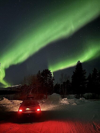 A car driving on a snow-covered road with the Northern Lights in the background. 5