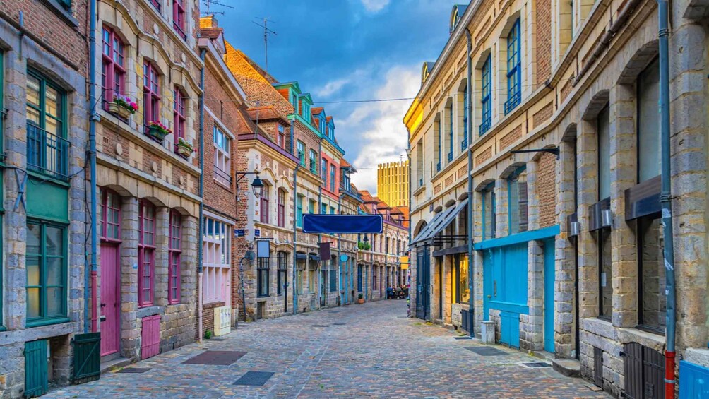 A cobblestone street lined with colorful buildings, a clear sky, and a blue sign. 4