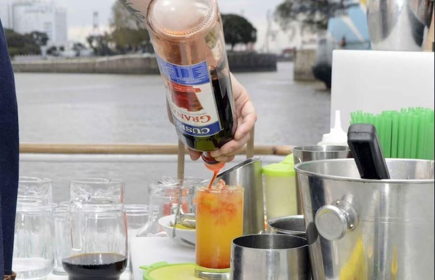 A person pouring a drink from a bottle into a glass. 5