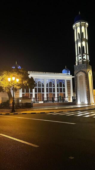 A mosque with a minaret and a large dome, illuminated at night. 4