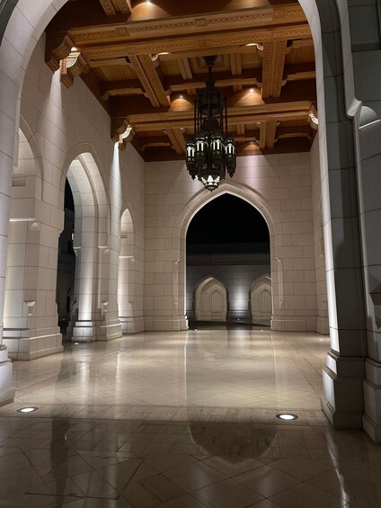 An interior corridor with arched ceilings, a chandelier, and tiled flooring. 2