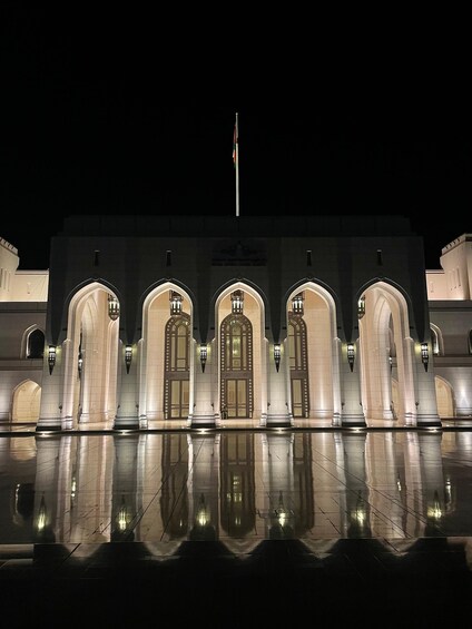 A grand building with arched doorways and a flagpole. 3