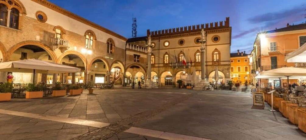 A historic square with arches, a fountain, and outdoor seating areas. 5