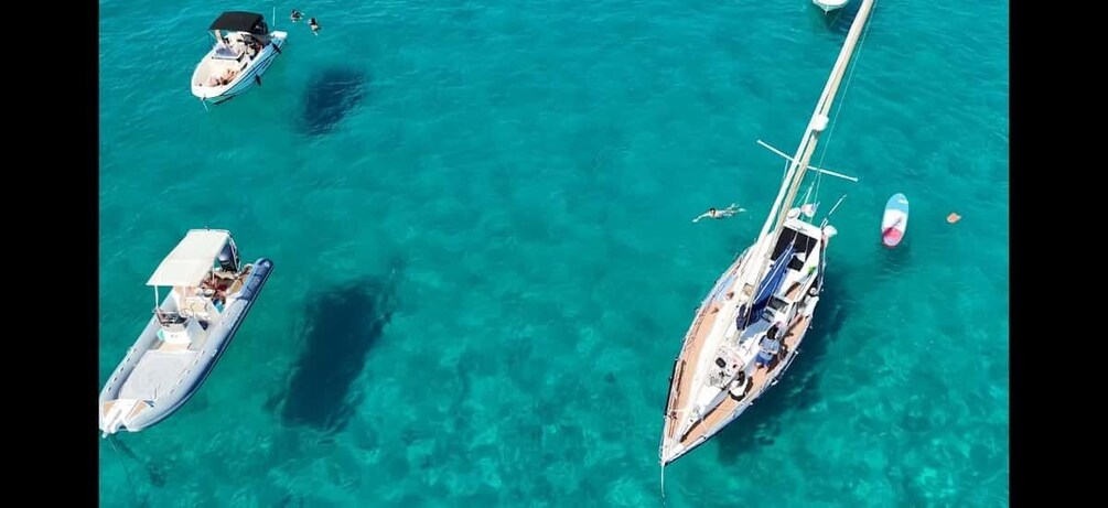 An aerial view of three boats on turquoise water. 1