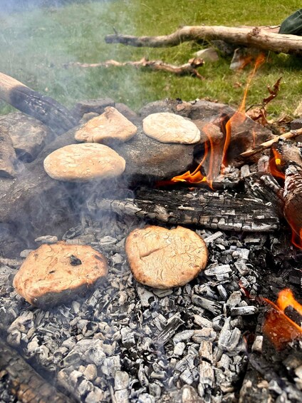 A campfire with several bread items cooking over it. 3