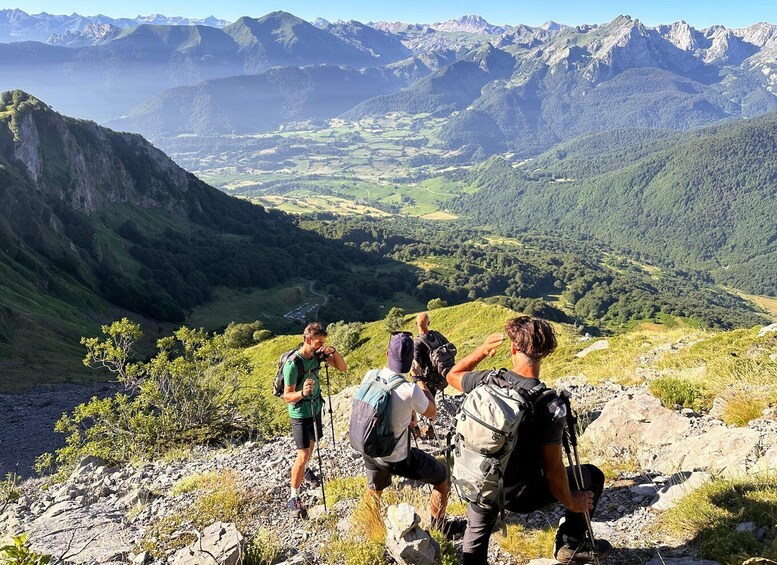 Three hikers on a mountain trail with a scenic view of a valley and distant mountains. 2