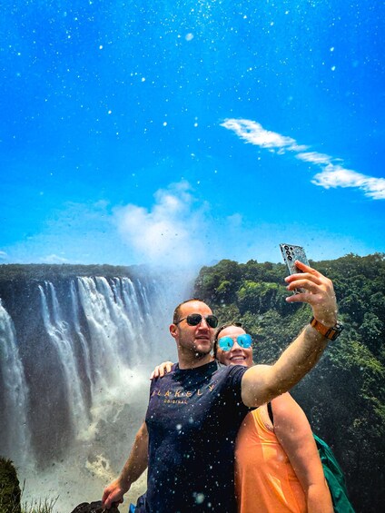 Two people taking a selfie with a waterfall in the background. 5