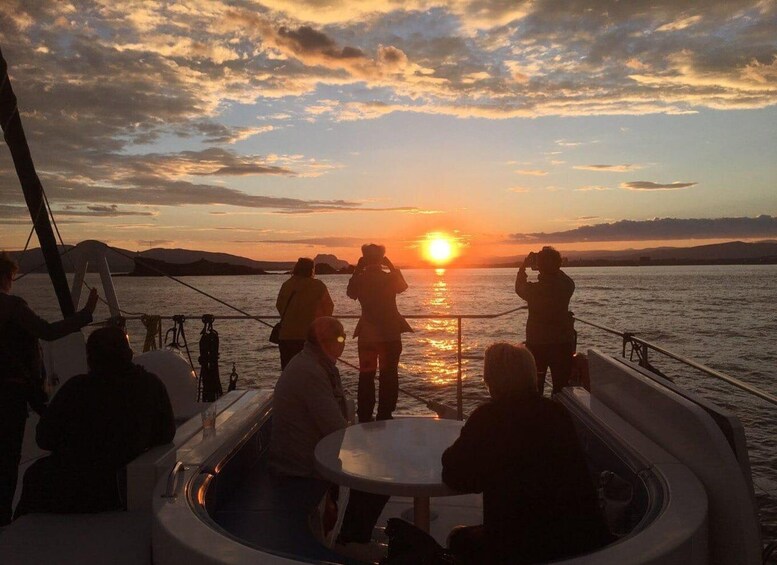 A sunset over a body of water with people on a boat. 3