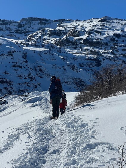 A snowy mountain path with a person and a child walking. 2
