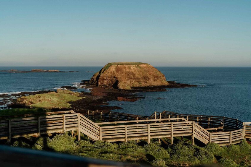 A coastal landscape with a prominent hill and a wooden viewing platform. 4