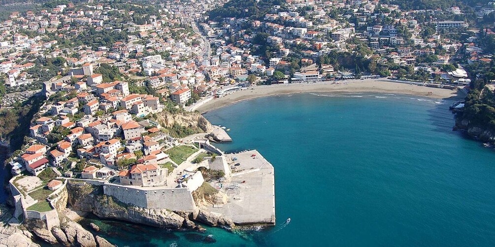 A coastal town with a fortified area, a beach, and surrounding residential buildings. 2