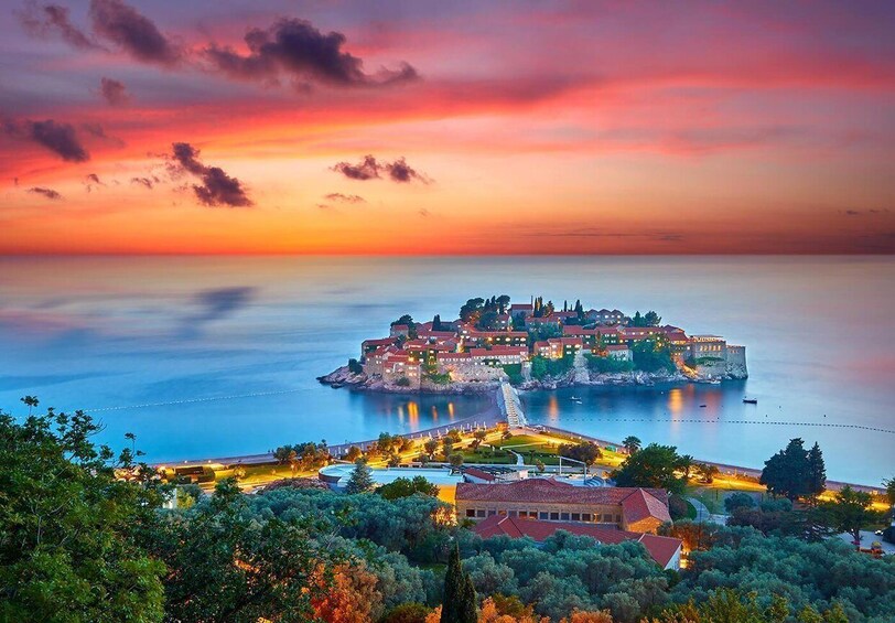 A coastal town at sunset with a prominent castle on a small island, surrounded by water. 5