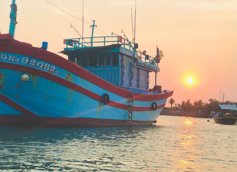 A large fishing boat with the number 92482 on its side, docked at sunset with the sun reflecting on the water. 5