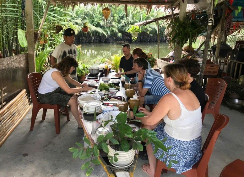 A group of people dining outdoors at a table with various dishes and drinks. 3