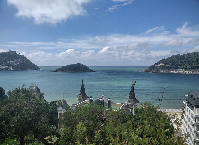 A coastal landscape with a clear sky, a small island, and buildings in the foreground. 4