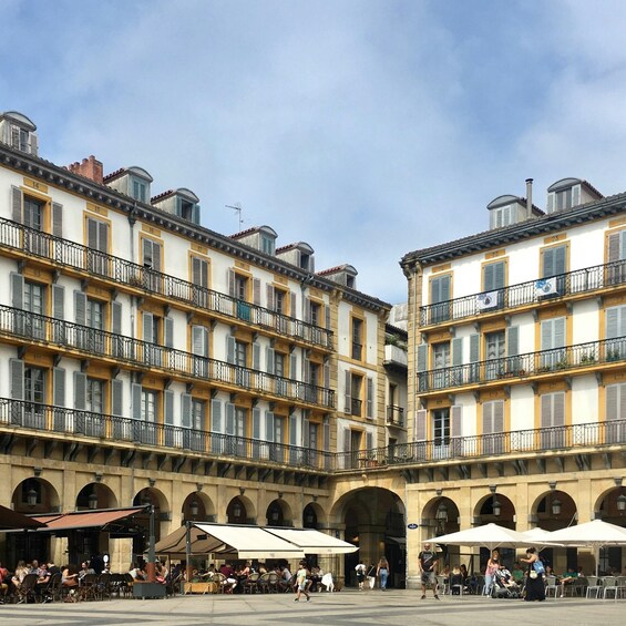 A courtyard with outdoor seating, surrounded by historic buildings with balconies and arched windows. 3