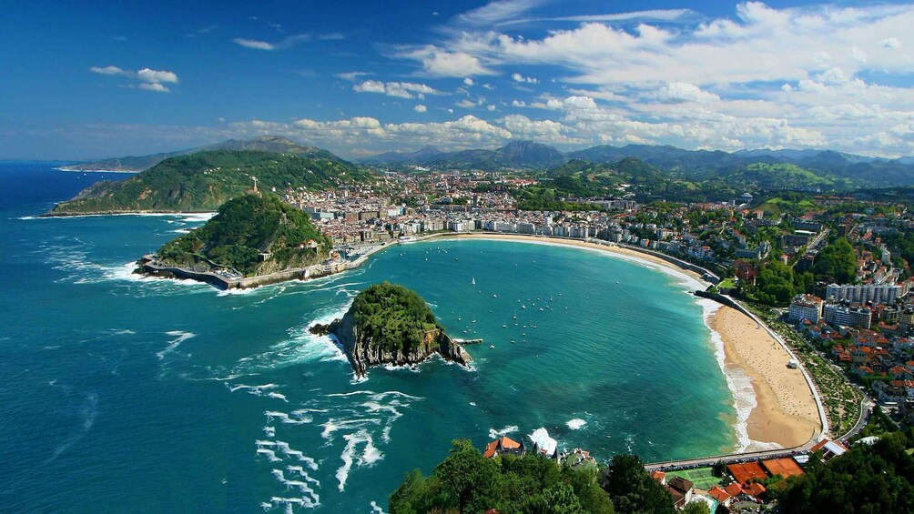 A coastal city with a bay, a beach, and a mountainous backdrop. 2
