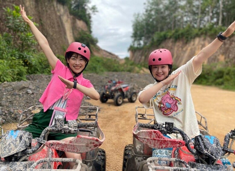 Twee personen op quads, met omhooggestoken armen, ter bescherming een helm op, en een rotsachtig landschap op de achtergrond. 5