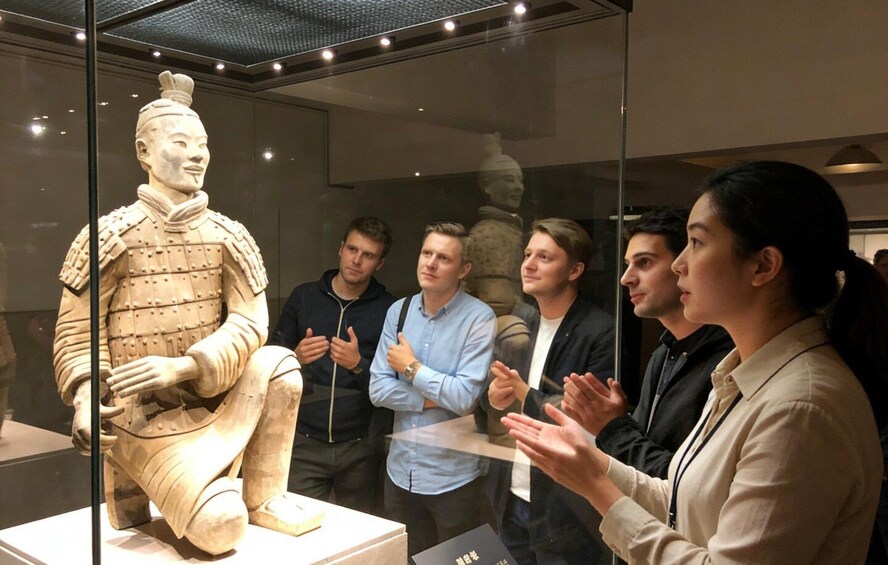 Ryhmä ihmisiä katselee terrakottasoturin patsaasta museossa. 3