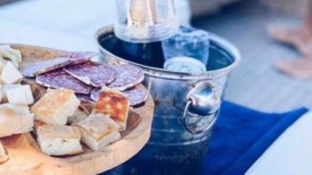 A wooden board with various types of cured meats and a metal container with a pump, likely used for dispensing a condiment or sauce. 3