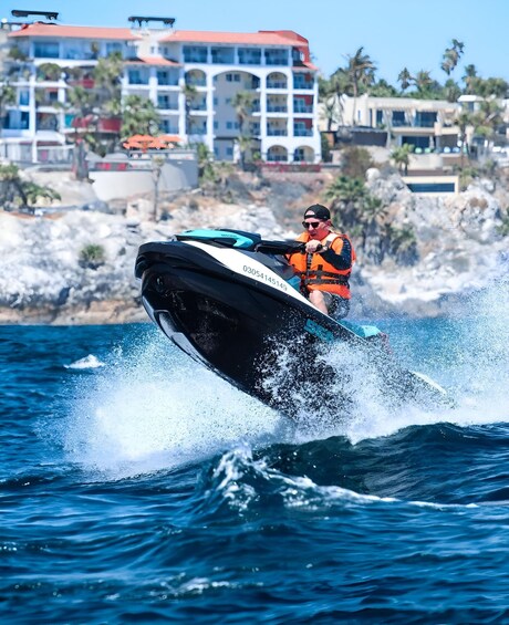 A person jet-skiing on a body of water with buildings in the background. 3