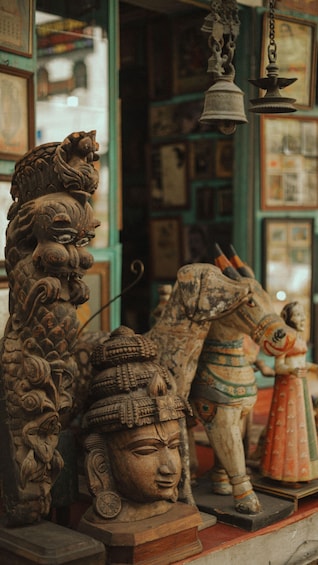 A collection of intricately carved statues, including a lion, a human figure, and a horse, displayed in a shop with green walls and various items in the background. 2