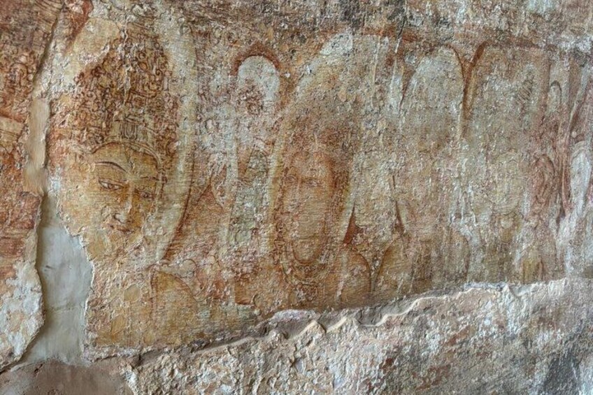 A weathered stone wall with ancient carvings, including a human figure and some text. 5
