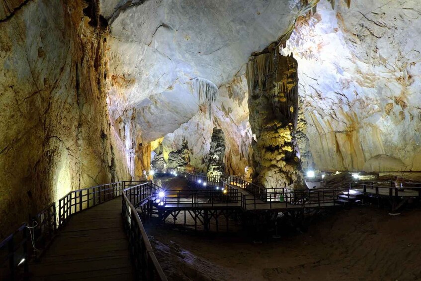 A cave with illuminated stalactites and a wooden walkway. 1