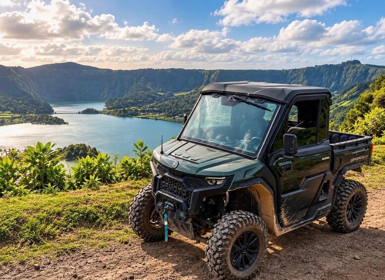 A UFORCE SUV parked on a dirt path overlooking a lake surrounded by hills. 1