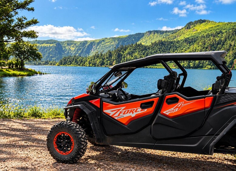A red and black ATV parked by a lake with a forested mountain in the background. 2