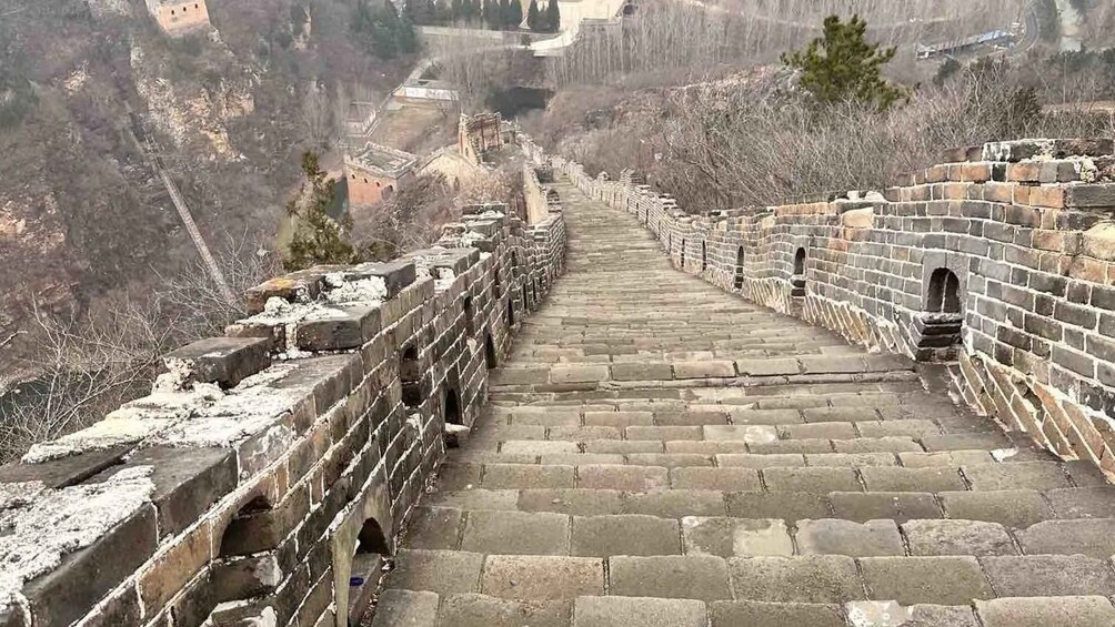 The Great Wall of China with a snow-covered path and surrounding barren landscape. 5