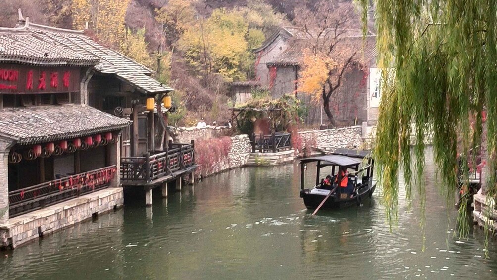A traditional Chinese waterway with a boat, buildings, and a weeping willow. 2