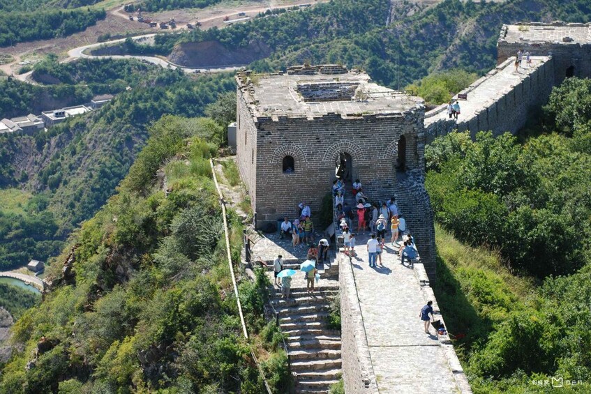 A section of the Great Wall of China with tourists walking along it. 3