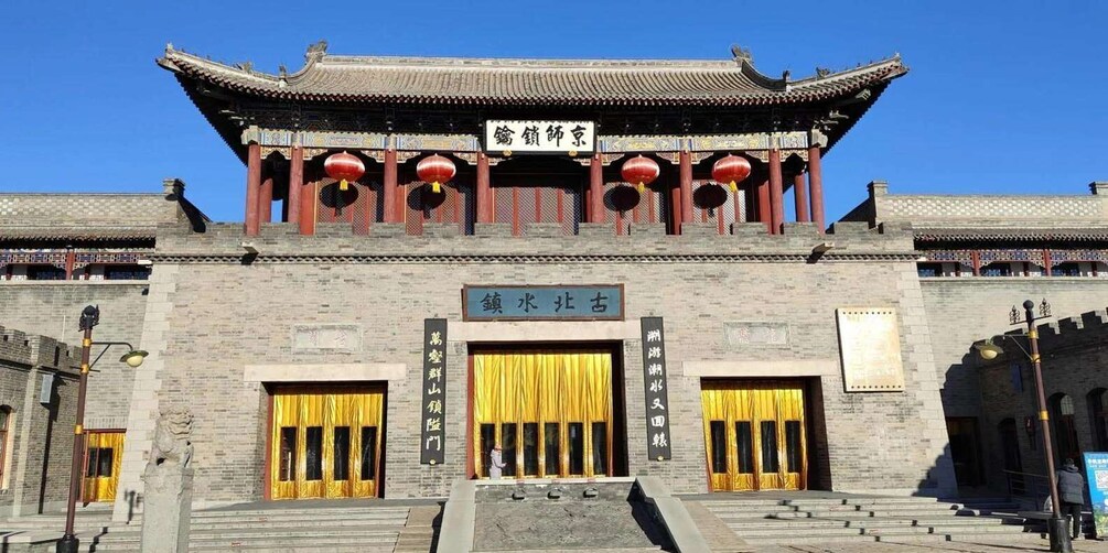 A traditional Chinese building with a tiled roof, red lanterns, and golden curtains. 1