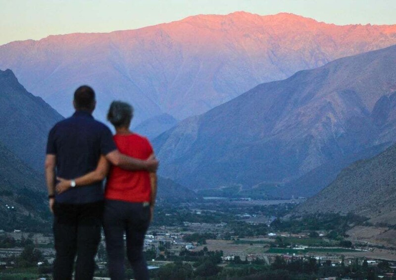 Two people standing and looking at a mountainous landscape with a valley below. 4
