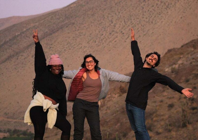Three people standing with arms raised in a mountainous landscape. 5