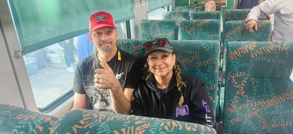 Two people seated on a bus with patterned seats. 3
