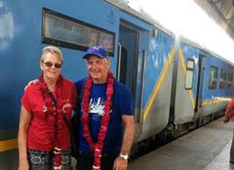 Two people standing in front of a train with a blue and yellow design. 4