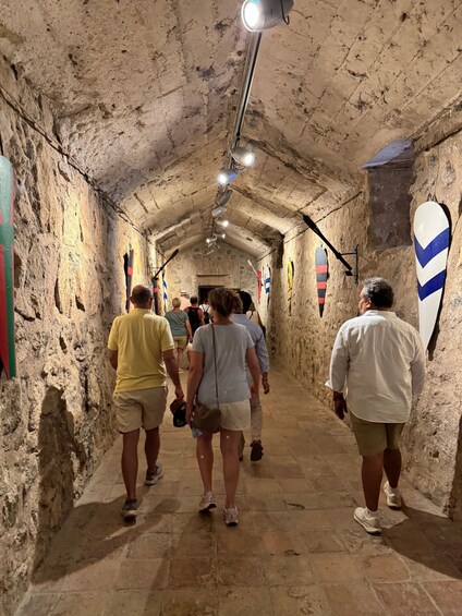 A stone tunnel with people walking through, illuminated by overhead lights. 2