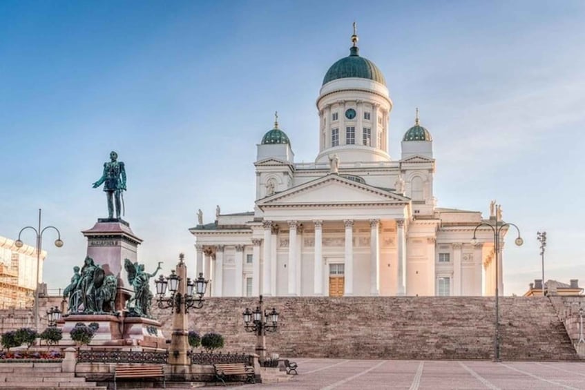 A large white building with a green dome and columns, a statue, and a fountain. 1