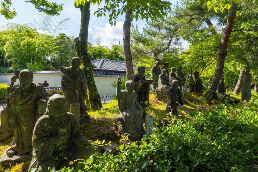 A serene garden with stone statues of various figures, surrounded by lush greenery and trees. 4