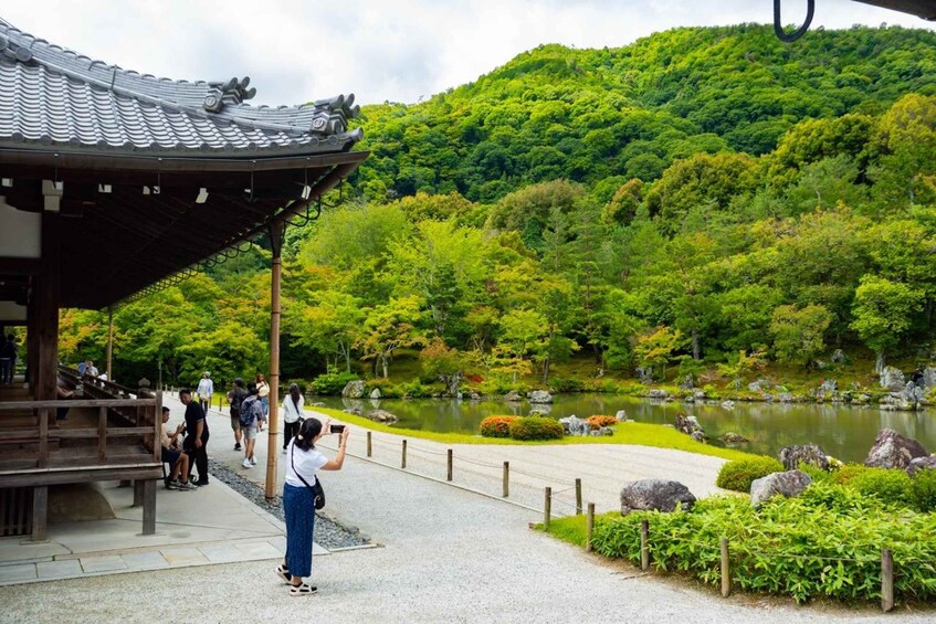 A traditional Japanese garden with a wooden structure, a pond, and lush greenery. 5