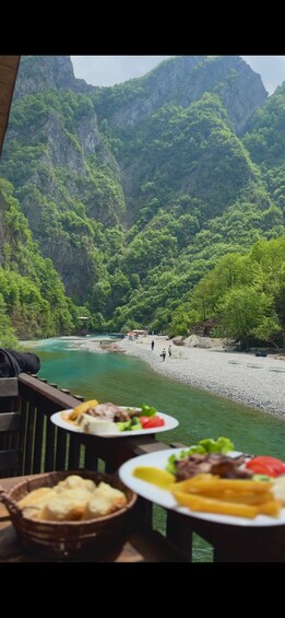 A table with food and a river with mountains in the background. 4