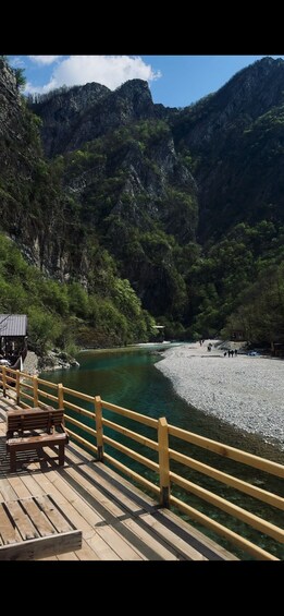 A wooden deck overlooking a river with a rocky mountain backdrop. 3