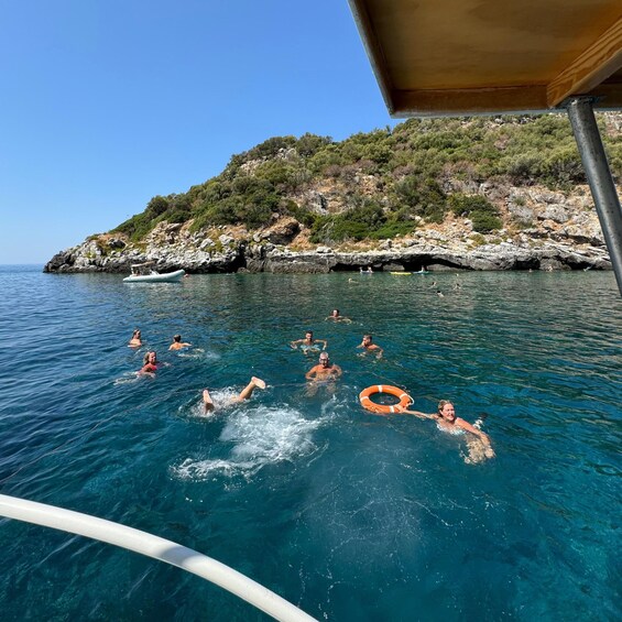 People swimming in the sea with a rocky island in the background. 5