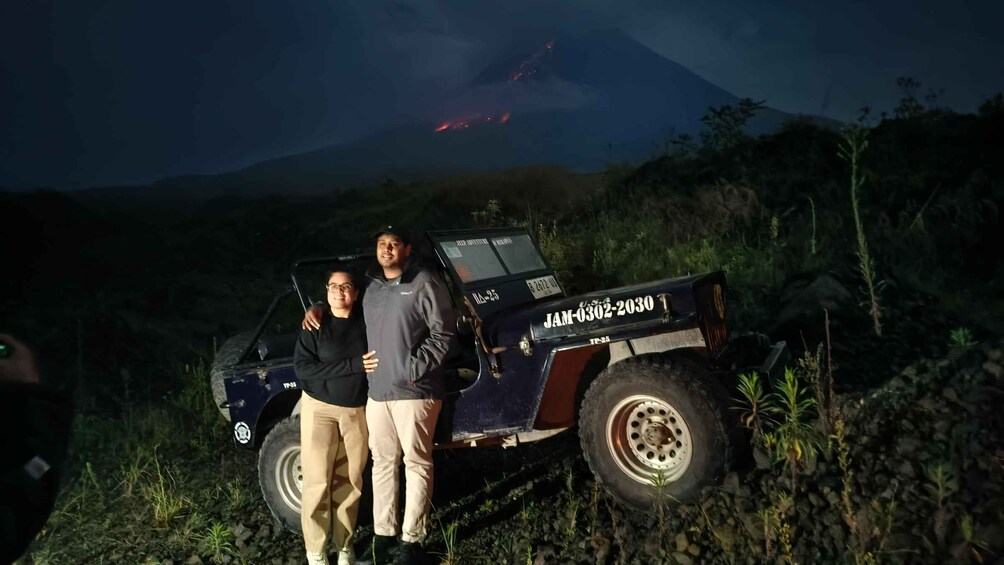 A vehicle with a license plate 'JAM-032-2030' parked on a rocky terrain with a volcano in the background. 1