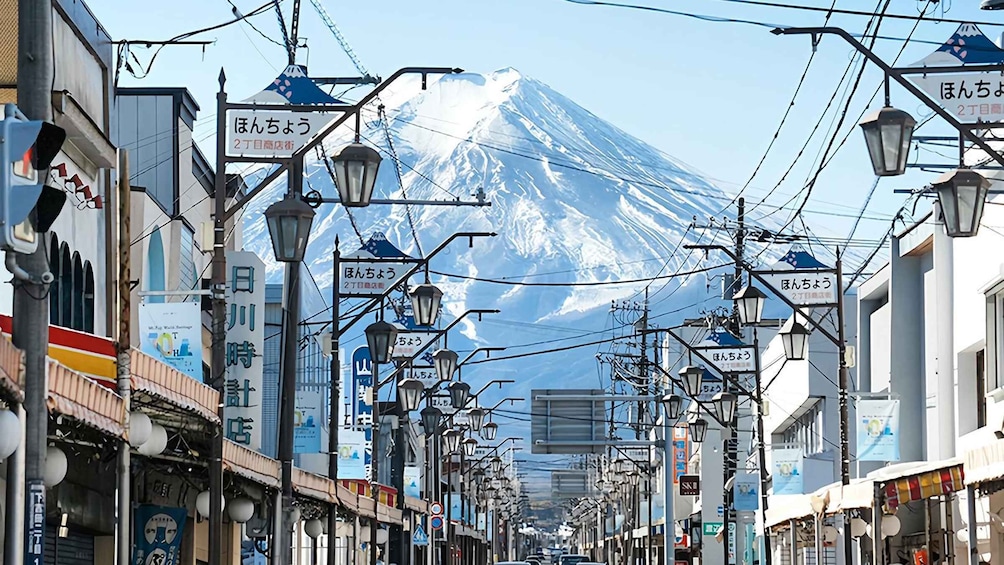A street with shops and signs, a mountain in the background, and power lines overhead. 2