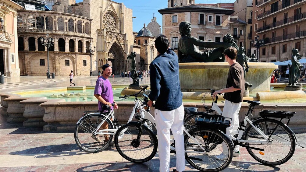 A historic square with a fountain, people, and bicycles. 3