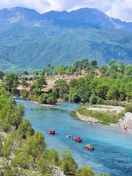 A river with several red boats, surrounded by lush green trees and mountains in the background. 4